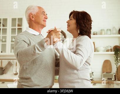 beautiful elderly married couple is dancing in the room. Pensioners are happy together. Stock Photo