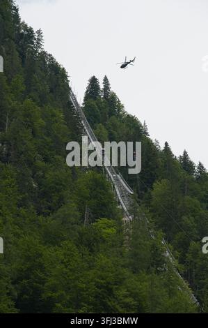 Hallstatt, Austria - July 14, 2026: Helicopter descends toward steep funicular tracks during renovation operations on the Salzbergbahn in Hallstatt. Stock Photo