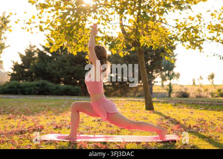 Fit sportswoman practicing yoga outdoors in autumn park Stock Photo