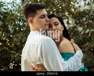 Young couple in love of different nationality hugging and kissing in the park. Asian woman and european man. Stock Photo