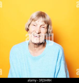 Portrait of beautiful older woman smiling over yellow background Stock Photo