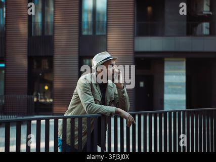 A young black man is talking on the phone, next to a business center. Stock Photo