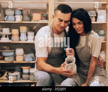 A young smiling couple works in a pottery workshop. Painting a vase. The concept of hobbies Stock Photo