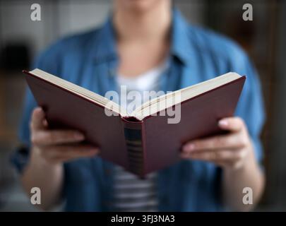 Woman holding open paper book in hands, reading best seller novel concept from bookstore bookshop Stock Photo