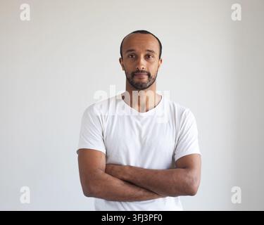 Portrait of young afro american man standing with arms crossed against light grey background Stock Photo