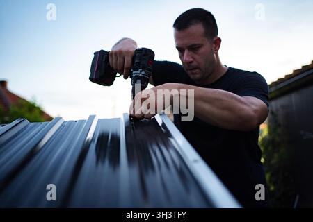 Man drilling into a metal panel, working on a construction project Stock Photo