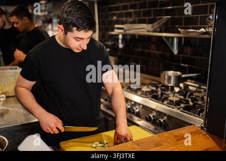 Chef chopping fresh vegetables in busy restaurant kitchen Stock Photo
