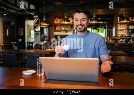 Smiling man telecommuting from cafe during video call Stock Photo