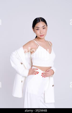 Young Asian Woman in White Suit Posing Elegant Vertical in Studio Stock Photo