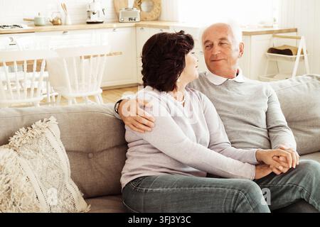 Senior lovely couple hugging sitting on sofa at home. Stock Photo