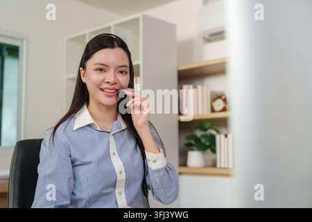Asian female customer service representative with headset working in office Stock Photo