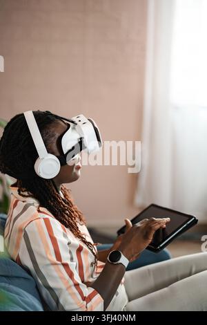 Young Black woman wearing VR headset using tablet Stock Photo