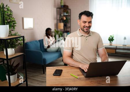 Man using laptop working from home with partner Stock Photo