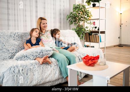 Mother and children relaxing on sofa watching television Stock Photo