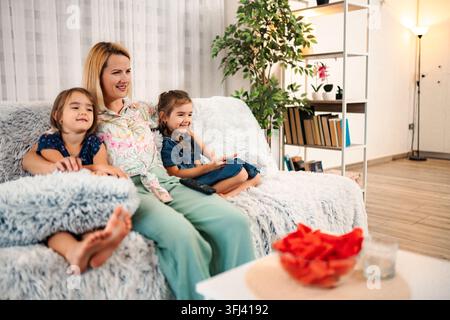 Mother and two daughters watching television at home Stock Photo