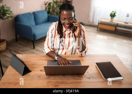 Adult woman working from home talking on phone Stock Photo