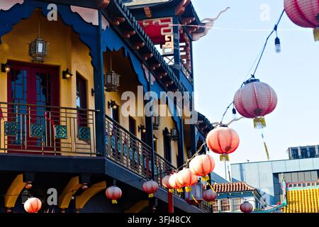 Colorful Chinatown building in Los Angeles with red lanterns, ornate balcony railings, yellow walls, blue trim, and bright cultural district details. Stock Photo