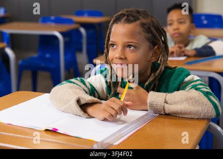 African American school boys sitting in class with notebook, clear ruler, holding pencil. Students, classroom, desks, chairs, wo Stock Photo