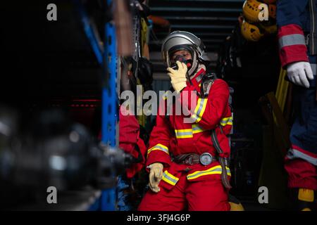 Firefighter wearing protective gear checks equipment and prepares for emergency response inside a rescue equipment area Stock Photo