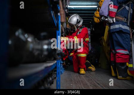 Firefighter wearing protective gear checks equipment and prepares for emergency response inside a rescue equipment area Stock Photo
