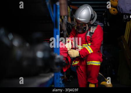 Firefighter wearing protective gear checks equipment and prepares for emergency response inside a rescue equipment area Stock Photo