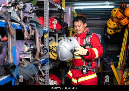 Firefighter wearing protective clothing and breathing equipment prepares a helmet inside an emergency rescue equipment storage area Stock Photo
