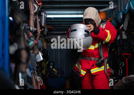 Firefighter wearing protective clothing and breathing equipment prepares a helmet inside an emergency rescue equipment storage area Stock Photo
