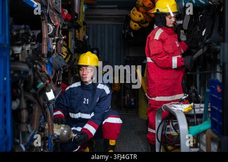 Firefighters prepare protective equipment and breathing apparatus inside a rescue equipment storage area before training Stock Photo