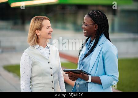 Diverse businesswomen smiling and collaborating with digital tablet Stock Photo