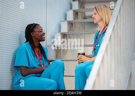 Diverse female nurses relaxing and talking during break time Stock Photo