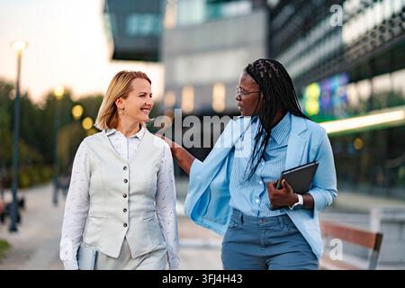 Diverse businesswomen walking together in city discussing work Stock Photo