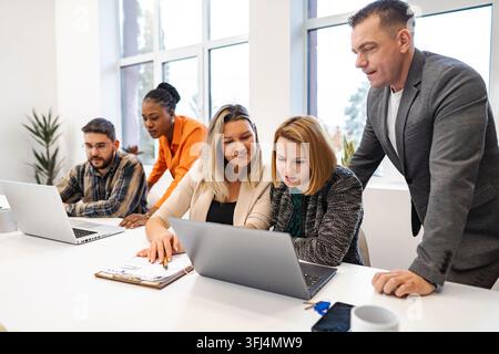 Business professionals collaborating on project using laptop in modern office Stock Photo
