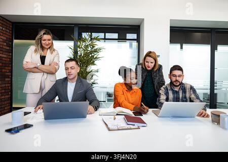 Team members working together on laptops and taking notes during a corporate meeting Stock Photo