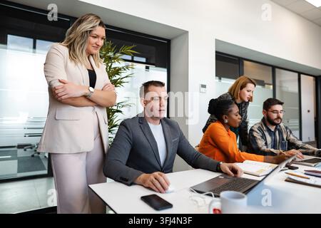 Business professionals collaborating and working together on laptops during a corporate meeting Stock Photo
