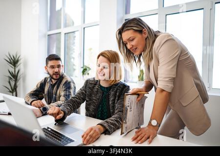 Business team discussing project details while working on a laptop Stock Photo