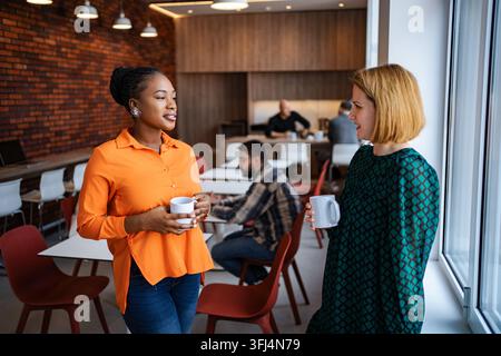 Two businesswomen talking in a modern office break room Stock Photo