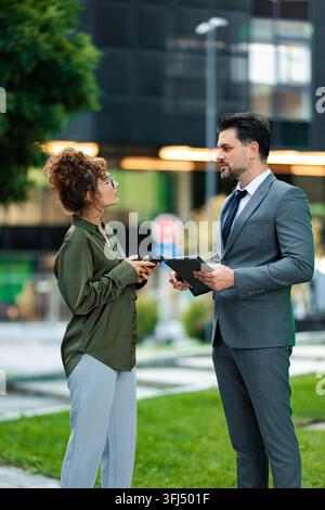 Business colleagues collaborating outdoors using digital tablet and smartphone Stock Photo
