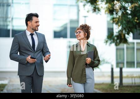 Business colleagues walking outdoors discussing new projects Stock Photo