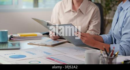 Cropped colleagues reviewing financial report folders at office desk for business audit Stock Photo