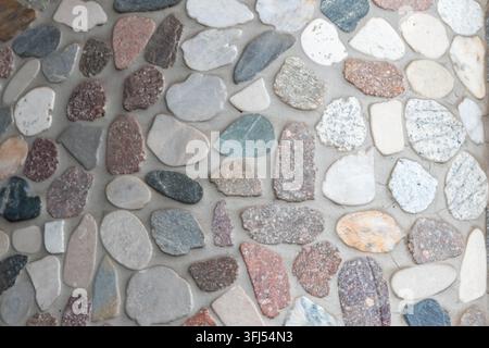 Elegant pebble background with river pebbles decorative wall design in concrete. Modern home decor with natural colorful pebbles as outdoor wall decor Stock Photo
