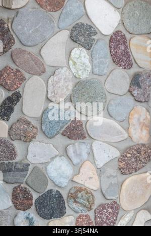 Elegant pebble background with river pebbles decorative wall design in concrete. Modern home decor with natural colorful pebbles as outdoor wall decor Stock Photo