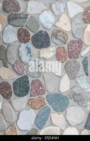 Elegant pebble background with river pebbles decorative wall design in concrete. Modern home decor with natural colorful pebbles as outdoor wall decor Stock Photo