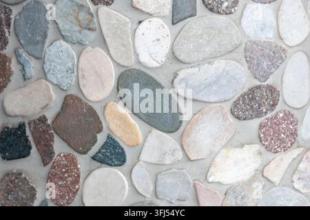 Elegant pebble background with river pebbles decorative wall design in concrete. Modern home decor with natural colorful pebbles as outdoor wall decor Stock Photo