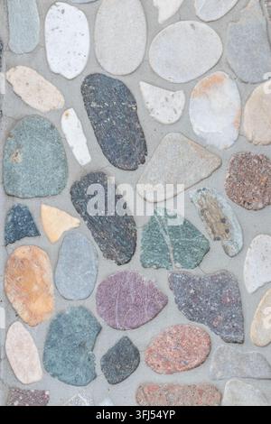 Elegant pebble background with river pebbles decorative wall design in concrete. Modern home decor with natural colorful pebbles as outdoor wall decor Stock Photo