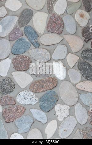 Elegant pebble background with river pebbles decorative wall design in concrete. Modern home decor with natural colorful pebbles as outdoor wall decor Stock Photo