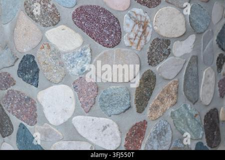 Elegant pebble background with river pebbles decorative wall design in concrete. Modern home decor with natural colorful pebbles as outdoor wall decor Stock Photo