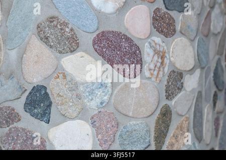 Elegant pebble background with river pebbles decorative wall design in concrete. Modern home decor with natural colorful pebbles as outdoor wall decor Stock Photo