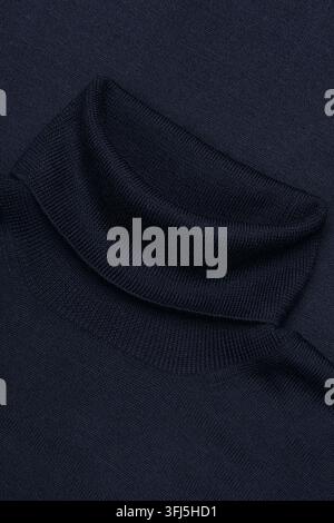 Close-up of dark navy knitted fabric arranged in soft folds, showing a detailed ribbed textile texture and deep shadows. Stock Photo