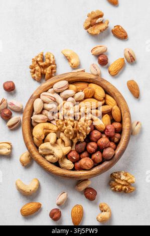 A mix of almonds, cashews, hazelnuts, walnuts, and pistachios in a wooden bowl on a light background. Healthy vegetarian snack concept. Top view, copy Stock Photo