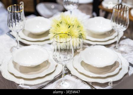 Formal dining table setting featuring white ceramic plates, floral centerpiece, elegant glassware, premium materials, sophisticated ambiance Stock Photo